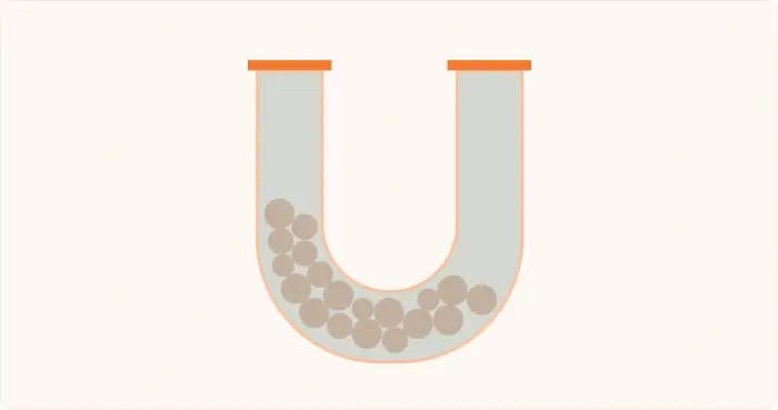 U-shaped tube with tan particles concentrated in the bottom curve.
